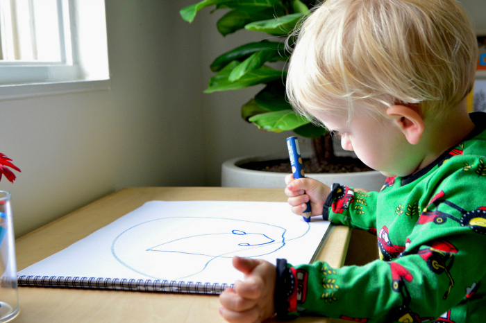 Kid drawing circular thing in white paper